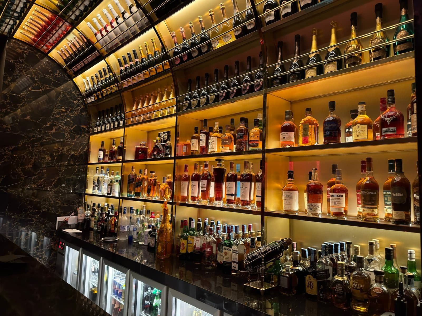 The backlit bottle wall behind the bar at TAMILA, Lisbon